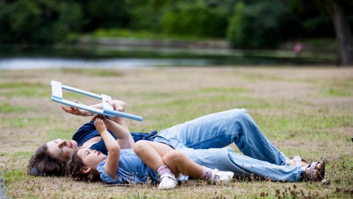 A parent and child lying on the grass by the lake at Claremont Landscape Garden